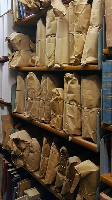 foto på en bokhylla full med bruna paket med pappsnören om