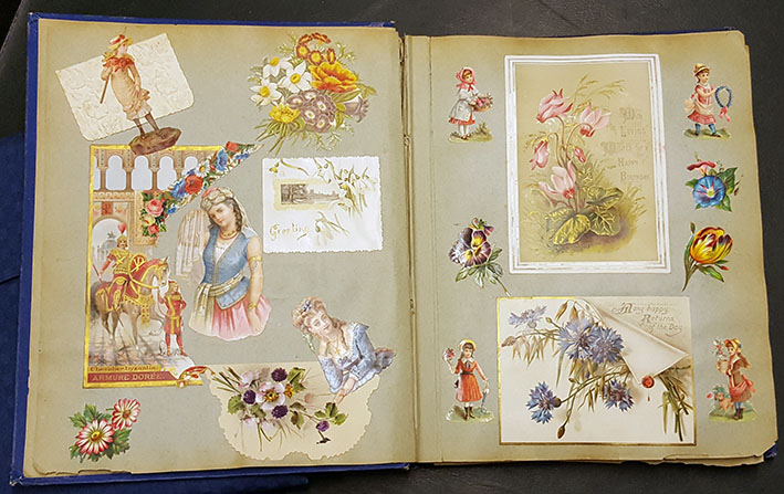 ett uppslag med fyra inklistrade vykort med blommotiv, med bokmärken med blommor och flickor klistrade runt om