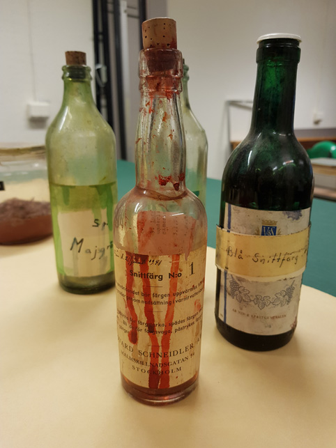 tre gamla glasflaskor på ett bord, samtliga innehållande rester av snittfärg